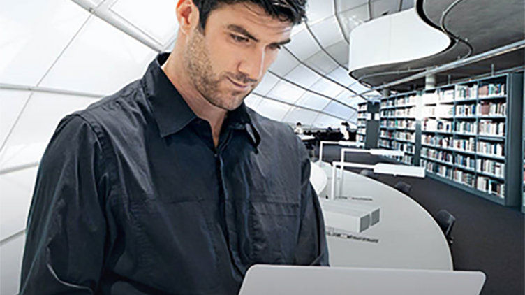 Mann hält ein Notebook in der Hand und schaut sich ein Webseminar an