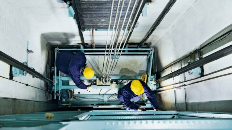 Zwei Mechaniker arbeiten an einem Aufzug Zwei Mechaniker arbeiten an einem Aufzug