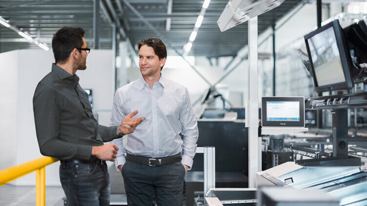 Two business people talking in a production hall.