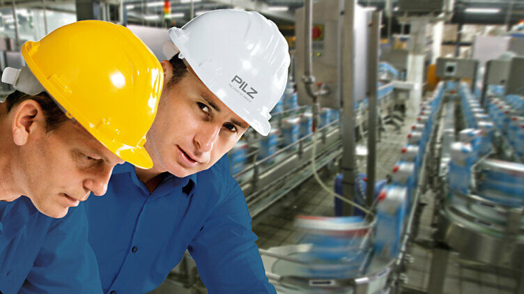 zwei Männer mit Helm stehen vor einer Maschine