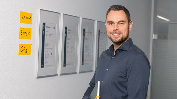Photo of a man in front of a wall with certificates in the background