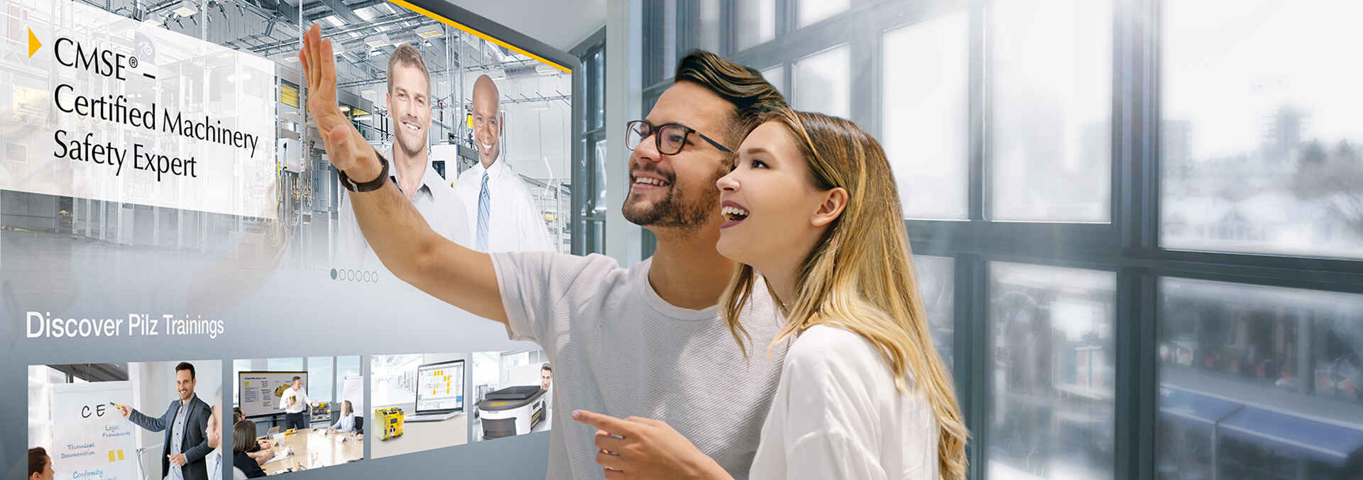 A man and a woman standing in front of a monitor showing the training.