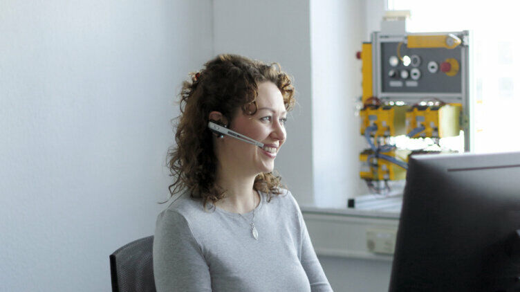 Frau mit Headset vor einem Bildschirm